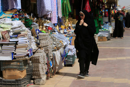 A woman walks past a shop selling ÒturbaÓ, a piece of stone or molded clay made of local soil, in Najaf, Iraq April 3, 2018. REUTERS/Alaa Al-Marjani