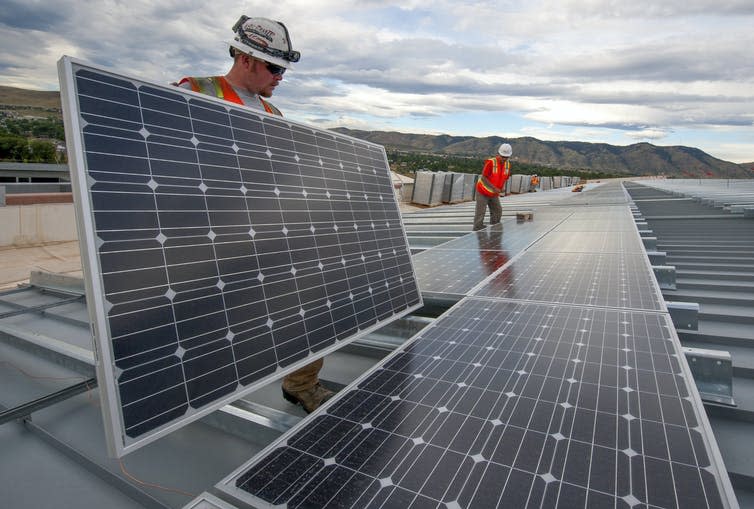 Two people install solar panels