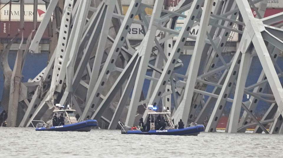 Police boats work around a cargo ship that is stuck under part of the structure of the Francis Scott Key Bridge after the ship hit the bridge Wednesday, March 27, 2024, in Baltimore. (AP Photo/Steve Helber)