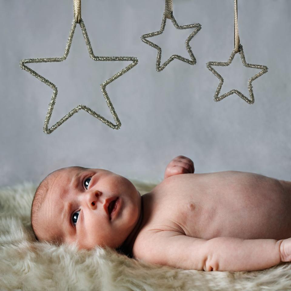 Portrait of a newborn baby lying under stars.