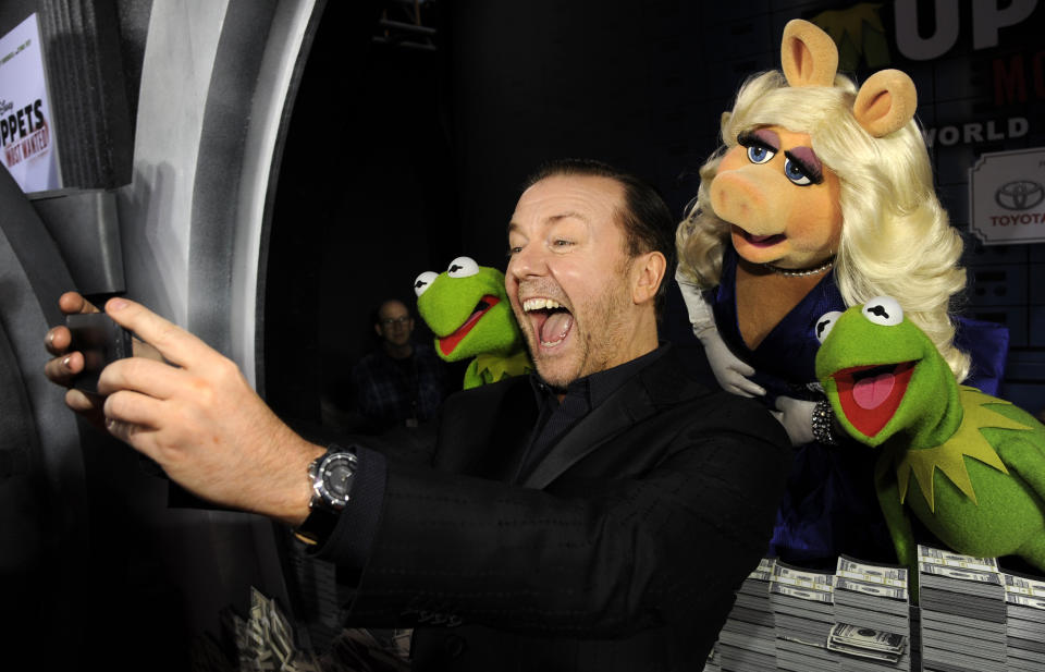 FILE - In this March 11, 2014 file photo, "Muppets Most Wanted" cast member Ricky Gervais photographs himself with fellow cast members, from left, Constantine, Miss Piggy and Kermit the Frog at the premiere of the film in Los Angeles. Gervais is 59 on June 25. (Photo by Chris Pizzello/Invision/AP, File)