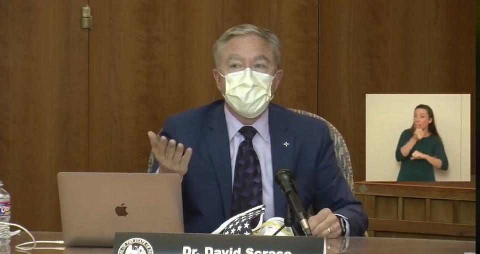 New Mexico Human Services Secretary Dr. David Scrase, who is also acting state Health Secretary, demonstrates proper mask-wearing during a virtual news conference from the state Capitol building in Santa Fe on Wednesday, July 1, 2020.