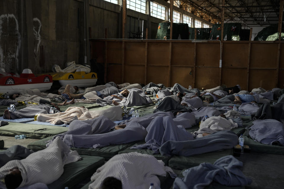 Survivors of a shipwreck sleep at a warehouse at the port in Kalamata town, about 240 kilometers (150 miles) southwest of Athens, Wednesday, June 14, 2023. A fishing boat carrying migrants capsized and sank off the coast of Greece on Wednesday, authorities said, leaving at least 78 people dead and many dozens feared missing in one of the worst disasters of its kind this year. (AP Photos/Thanassis Stavrakis)