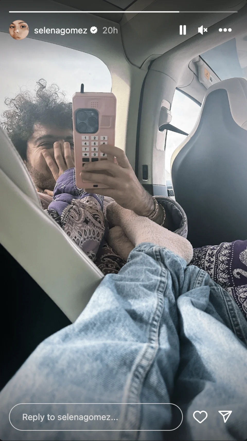 Gomez rubs her feet in fuzzy socks on Benny Blanco inside a vehicle. He's holding a pink iphone. (@selenagomez / Instagram)