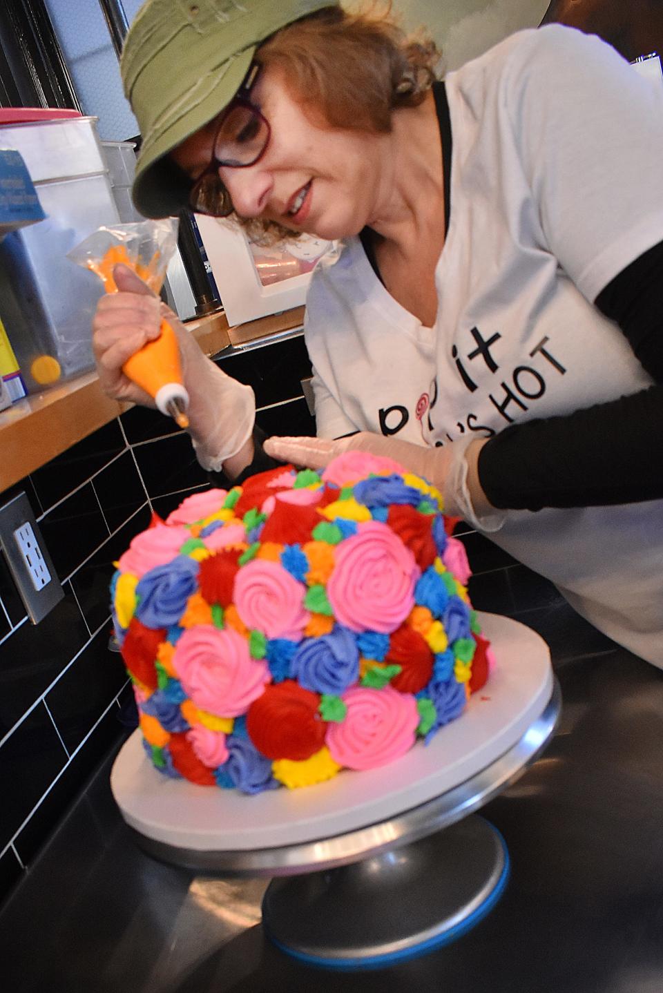 Lisa Petrizzi-Geller, owner of Pop Culture, works on a cake in her new Fall River shop.