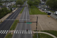 A pedestrian crosses at the westbound side of Roosevelt Avenue on at the Banks Way crosswalk, Thursday, May 12, 2022, in Philadelphia. Roosevelt Boulevard is an almost 14-mile maze of chaotic traffic patterns that passes through some of the city's most diverse neighborhoods and Census tracts with the highest poverty rates. Driving can be dangerous with cars traversing between inner and outer lanes, but biking or walking on the boulevard can be even worse with some pedestrian crossings longer than a football field and taking four light cycles to cross. (AP Photo/Julio Cortez)