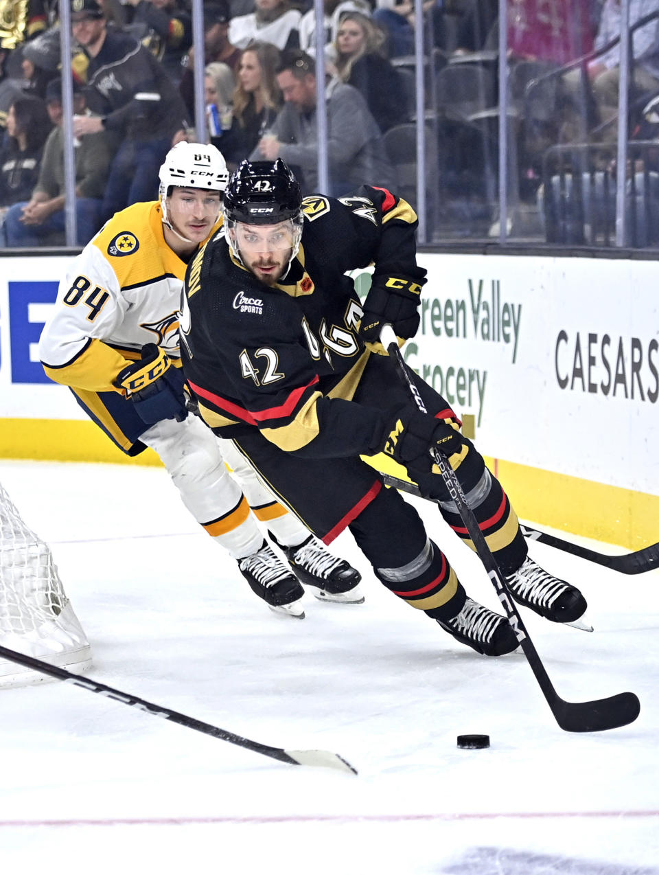 Vegas Golden Knights defenseman Daniil Miromanov (42) skate with the puck ahead of Nashville Predators left wing Tanner Jeannot (84) during the first period of an NHL hockey game Saturday, Dec. 31, 2022, in Las Vegas. (AP Photo/David Becker)