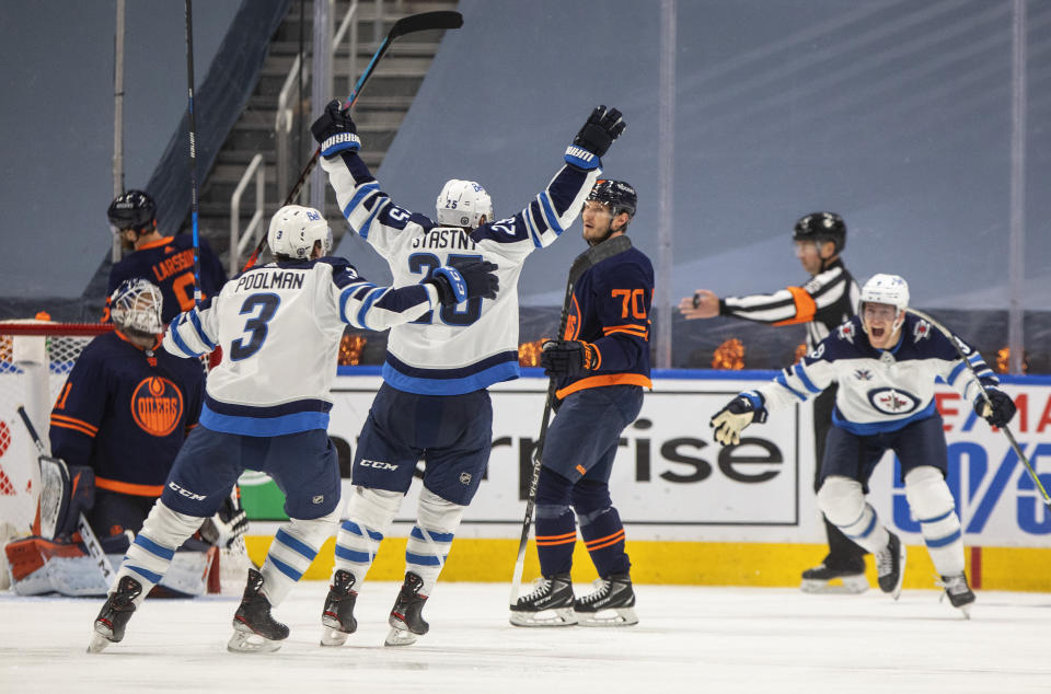 FILE - Edmonton Oilers goalie Mike Smith (41) and Ryan McLeod (70) look on as Winnipeg Jets' Tucker Poolman (3) and Paul Stastny (25) celebrate a goal during overtime in Game 2 of an NHL hockey Stanley Cup first-round playoff series in Edmonton, Alberta, in this Friday, May 21, 2021, file photo. A pandemic postseason outside a bubble has led to some thrilling hockey after an exhausting, condensed 56-game grind. (Jason Franson/The Canadian Press via AP)