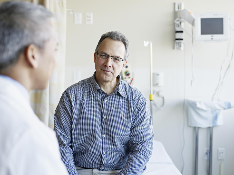 Doctor talking to mature male patient in hospital room