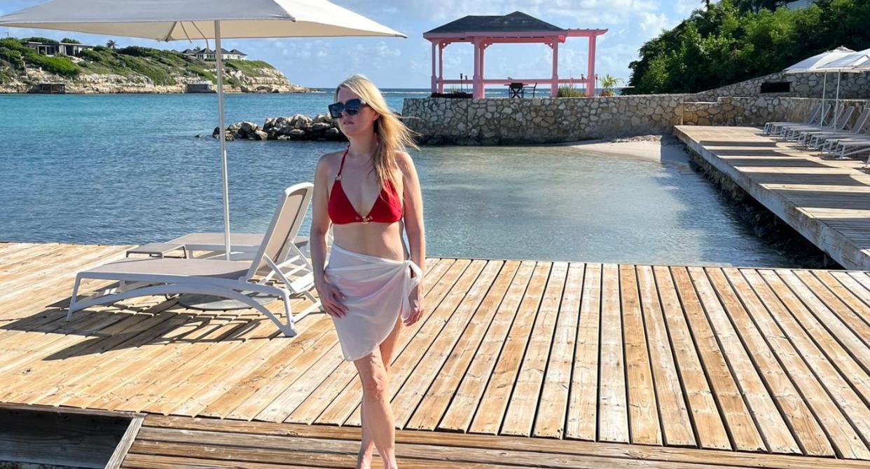 Claire Sisk in a sarong and bikini top on holiday infront of the sea and sun loungers. (Supplied)