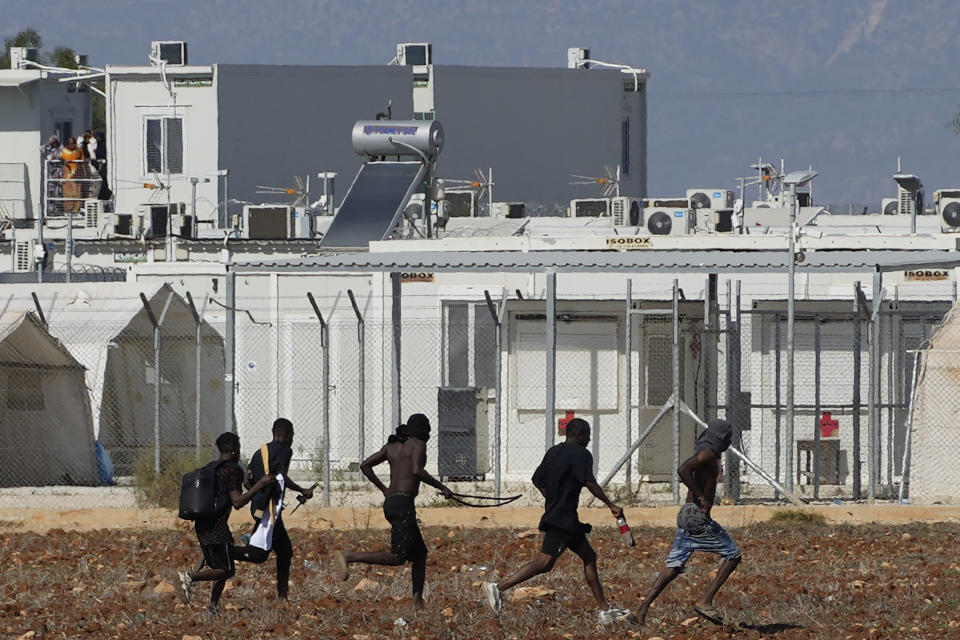 FILE - Migrants, holding what appear to be like weapons, flee the camp near the village of Kokkinotrimithia on the outskirts of the capital Nicosia, Cyprus, Friday, Oct. 28, 2022. The president of Cyprus Nikos Christodoulides said on Tuesday, April 2, 2024, he has personally asked the head of the European Union's executive arm to intercede with Lebanese authorities so that they could put a stop to boat loads of Syrian refugees from heading to the east Mediterranean island nation. (AP Photo/Petros Karadjias, File)