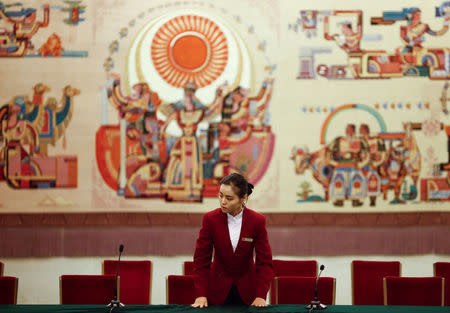 An attendant prepares a table for a session on the second day of the 19th National Congress of the Communist Party of China at the Great Hall of the People in Beijing, October 19, 2017. REUTERS/Thomas Peter