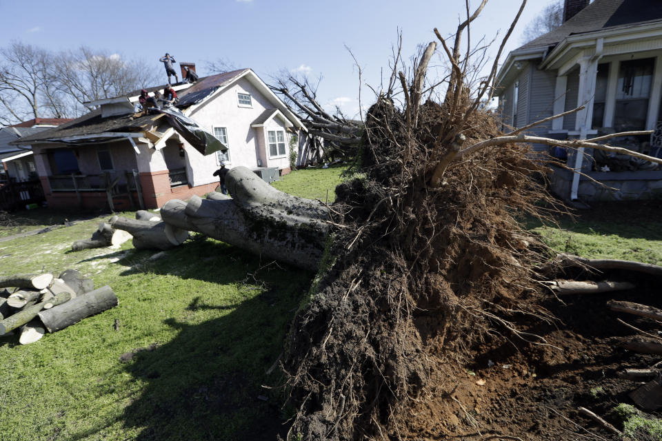 Workers repair a roof damaged by a tree uprooted by a tornado Friday, March 6, 2020, in Nashville, Tenn. Residents and businesses face a huge cleanup effort after tornadoes hit the state Tuesday. (AP Photo/Mark Humphrey)