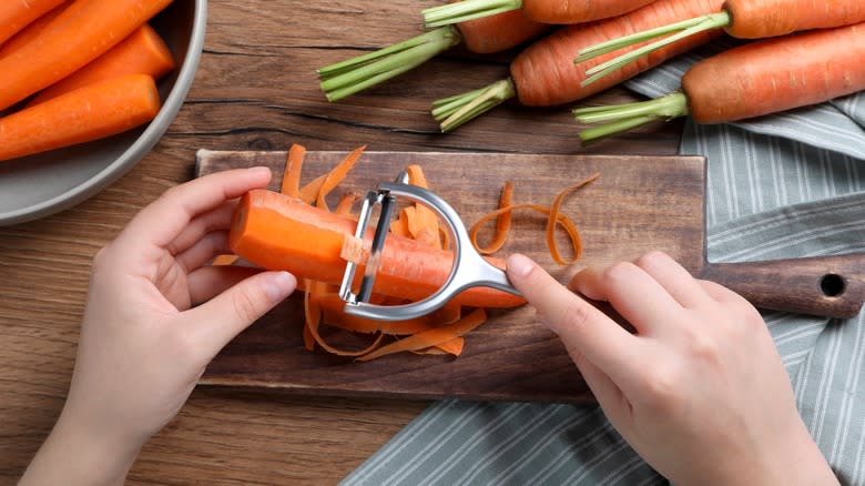 Person peeling carrots with a peeler