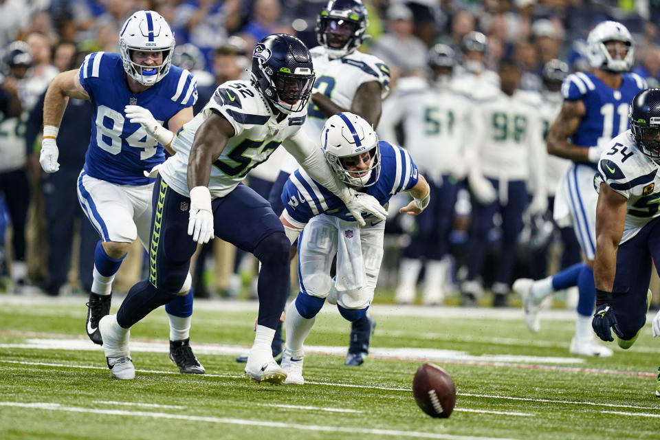 Seattle Seahawks defensive end Darrell Taylor (52) holds back Indianapolis Colts quarterback Carson Wentz (2) after Wentz fumbled in the first half of an NFL football game in Indianapolis, Sunday, Sept. 12, 2021. The Colts recovered the ball (AP Photo/Charlie Neibergall)