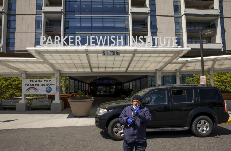 A security guard stands in the drive at the Parker Jewish Institute for Healthcare and Rehabilitation, Monday, May 4, 2020, in the Queens borough of New York. New York state is reporting more than 1,700 previously undisclosed deaths at nursing homes and adult care facilities as the state faces scrutiny over how it's protected vulnerable residents during the coronavirus pandemic. Parker Jewish Institute reported the highest number of deaths: 71.(AP Photo/Marshall Ritzel)