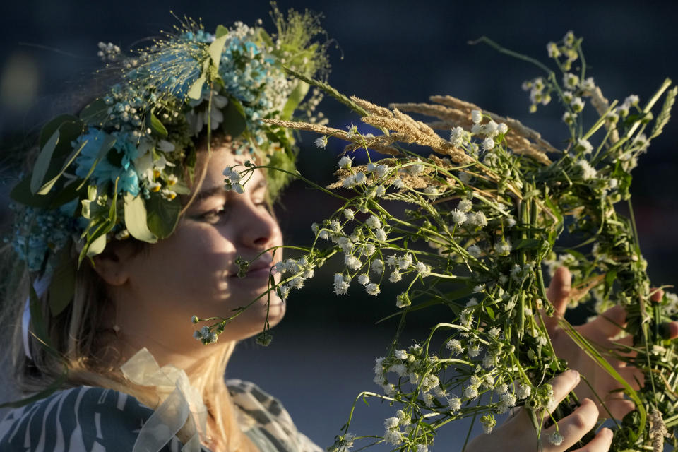 A young Ukrainian woman wearing an ear of grain braid holds grain and flowers during a traditional Ukrainian celebration of Kupalo Night, in Warsaw, Poland, on Saturday, June 22, 2024. Ukrainians in Warsaw jumped over a bonfire and floated braids to honor the vital powers of water and fire on the Vistula River bank Saturday night, as they celebrated their solstice tradition of Ivan Kupalo Night away from war-torn home. (AP Photo/Czarek Sokolowski)