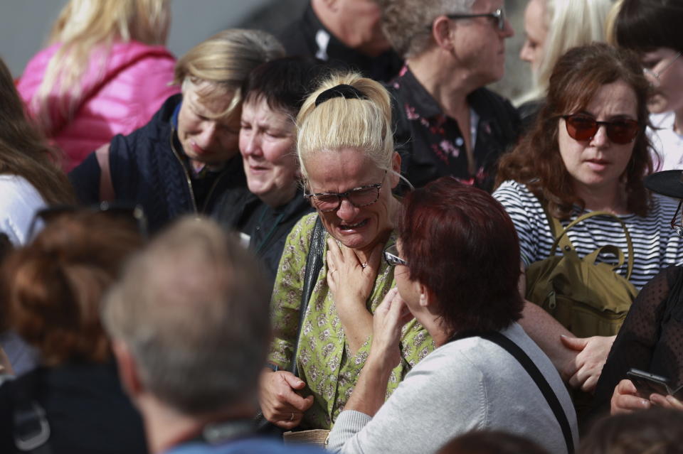 Sinead O'Connor fan, Ruth O'Shea, centre, stands outside the former home of Sinead O'Connor ahead of the late singer's funeral, in Bray, Co Wicklow, Ireland, Tuesday, Aug. 8, 2023. O’Connor’s family has invited the public to line the waterfront in Bray on Tuesday as her funeral procession passes by. Fans left handwritten notes outside her former home, thanking her for sharing her voice and her music. (Liam McBurneyPA via AP)