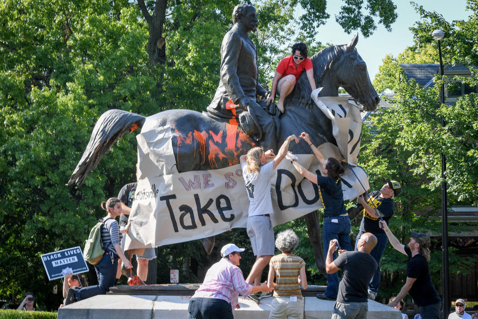 Members of a racial justice organization prepare to hang a banner that says, "Louisville, take it down" on a Confederate monument on Aug. 19. (Photo: Bryan Woolston / Reuters)