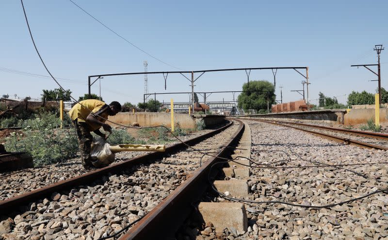 Imagen de archivo de un cable dañado en una vía férrea mientras un hombre busca material reciclable cerca de la vandalizada estación de Kliptown en Soweto, Sudáfrica.