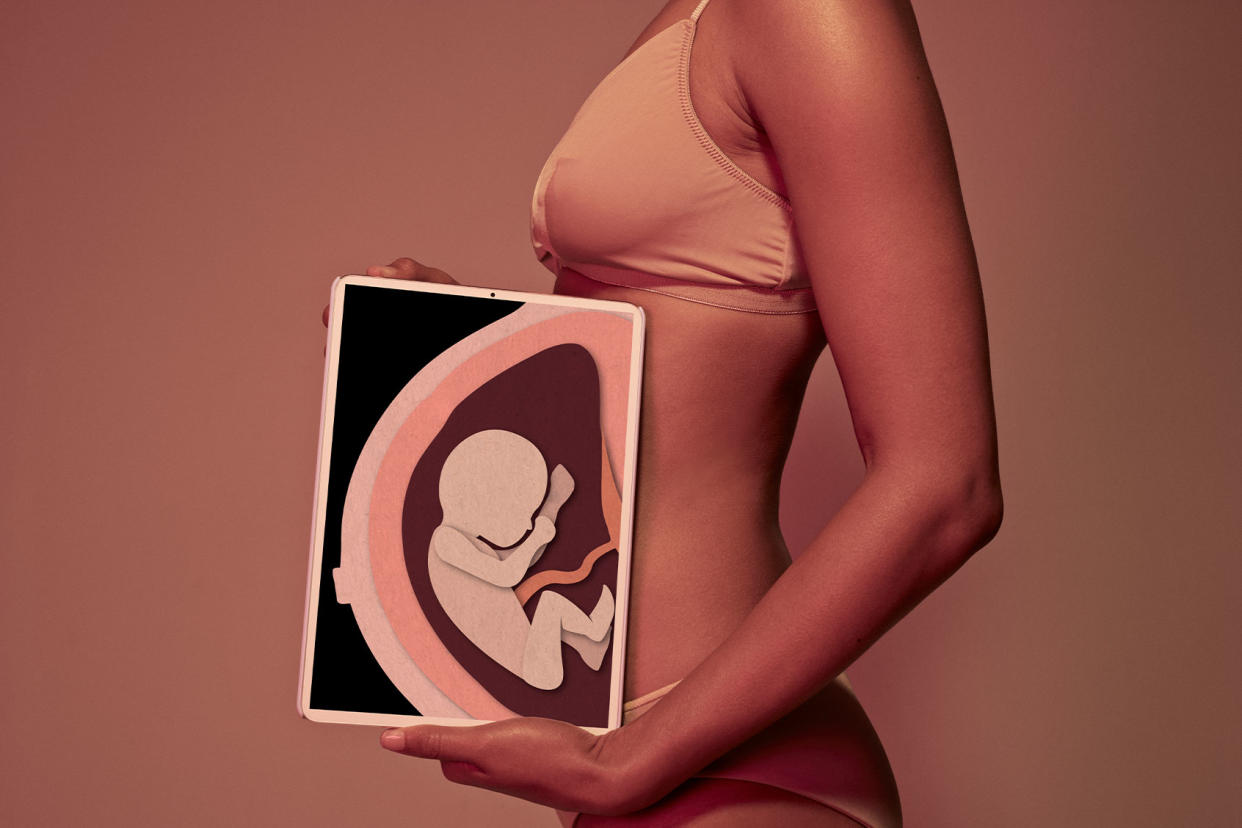 Woman holding tablet showing pregnancy illustration Getty Images/Klaus Vedfelt