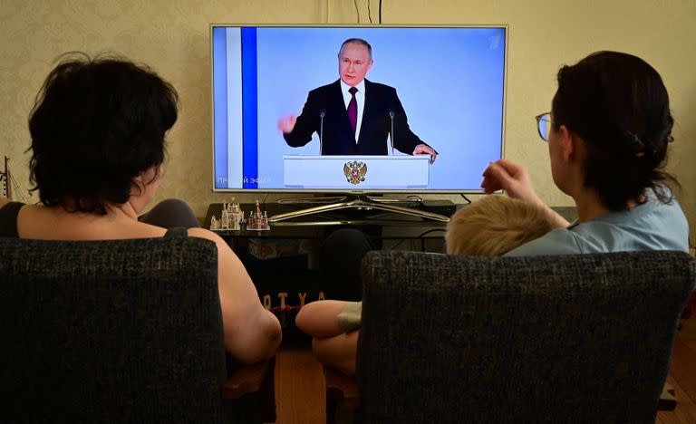 Una familia observa una transmisión de televisión del discurso anual del estado del presidente ruso Vladimir Putin en Moscú el 21 de febrero de 2023