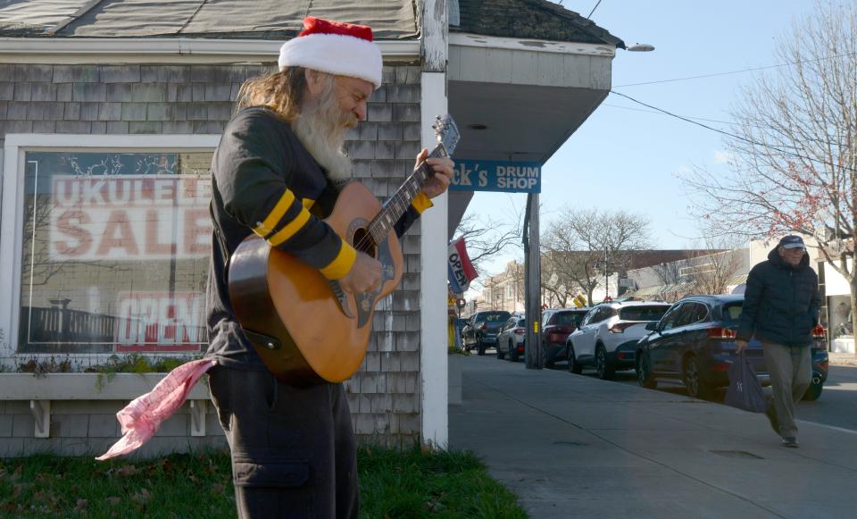Performer GOTHBRO, his stage name, found a spot in the sun to entertain pedestrians along Main Street Hyannis with some Christmas music on Thursday afternoon. Cape Cod Times/Steve Heaslip