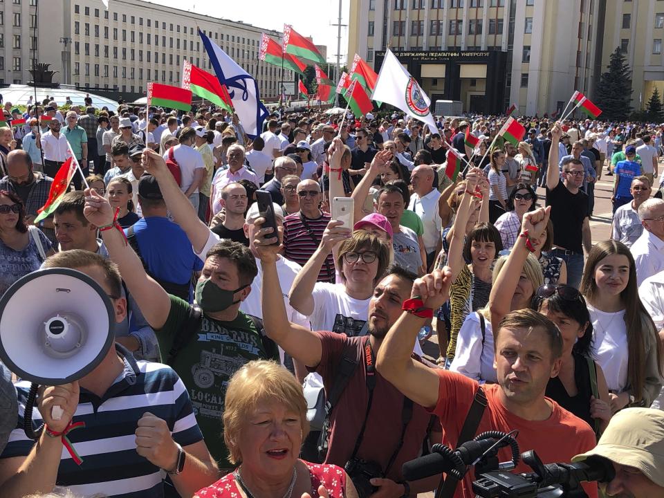 Hundreds of supporters of Belarusian President Alexander Lukashenko with Belarusian State flags gather at Independent Square of Minsk, Belarus, Sunday, Aug. 16, 2020. On Saturday, thousands of demonstrators rallied at the spot in Belarus' capital where a protester died in clashes with police, calling for Lukashenko to resign. (AP Photo/Sergei Grits)