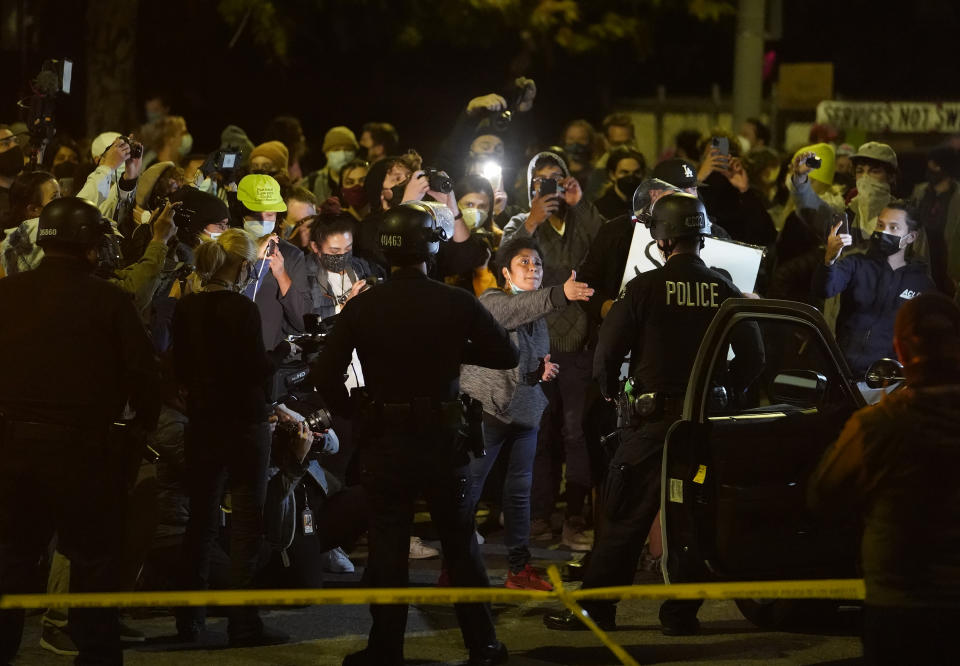 Homeless residents of Echo Park confront Los Angeles Police officers moving in to remove residents in the Echo Park Lake homeless encampment in Los Angeles late Wednesday, March 24, 2021. (AP Photo/Damian Dovarganes)