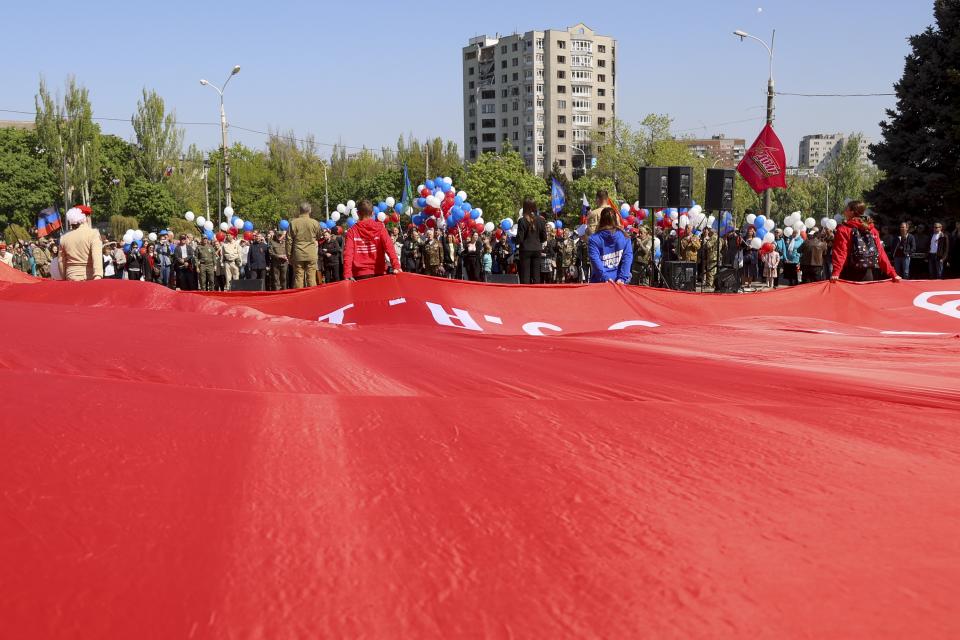 People carry a big replica of the Victory banner marking the 77th anniversary of the end of World War II in Mariupol, in territory under the government of the Donetsk People's Republic, eastern Ukraine, Monday, May 9, 2022. (AP Photo/Alexei Alexandrov)