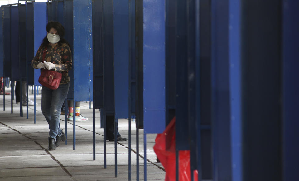 A woman leaves the voting booth during a referendum to decide whether the country should replace its 40-year-old constitution, in Santiago, Chile, Sunday, Oct. 25, 2020. (AP Photo/Esteban Felix)