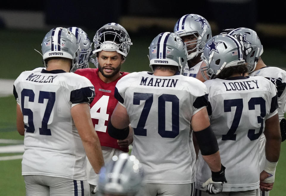 Dallas Cowboys quarterback Dak Prescott (4) speaks to offensive linemen Wyatt Miller (67) Zach Martin (70), Loe Looney (73) and others in a huddle during NFL football training camp in Frisco, Texas, Tuesday, Aug. 18, 2020. (AP Photo/LM Otero)