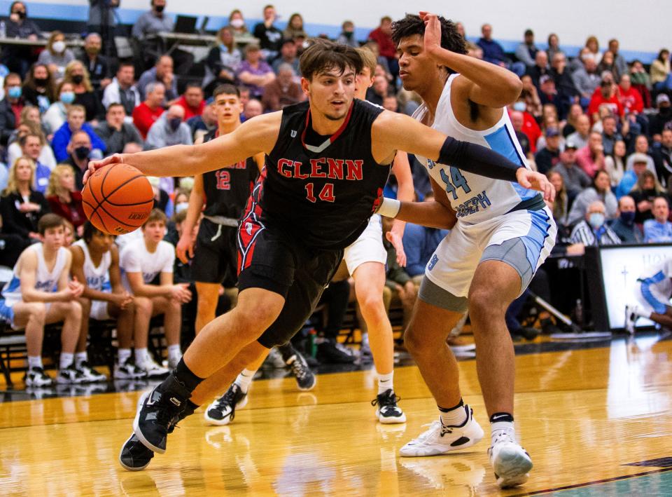 John Glenn's Brycen Hannah drives against Saint Joseph's Julian Kamanda during the Saint Joseph vs. John Glenn boys basketball game Friday, Jan. 14, 2022 at Saint Joseph High School in South Bend. 