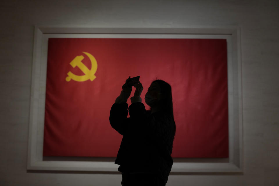 A visitor takes photo near a Chinese Communist Party flag at the Museum of the Communist Party of China in Beijing, China, Friday, Nov. 12, 2021. China says it is a nation "ruled by law," but the Communist Party ultimately holds sway and there are large gray areas of enforcement. Control over the press and social media allows authorities to keep word of disappearances quiet and to stonewall critics, although such news often gradually surfaces through underground and foreign sources. (AP Photo/Ng Han Guan)