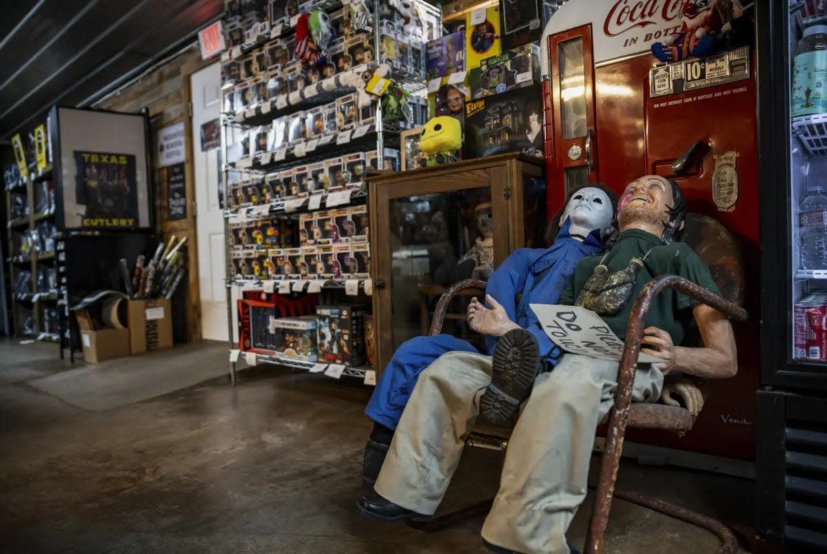 Two life-sized horror movie dummies sit in front of a movie prop vending machine at We Slaughter BBQ in Bastrop on Oct. 27. The roadside rest stop and tourist attraction, now restored, is one of several Central Texas locations where the 1974 film "Texas Chainsaw Massacre" was filmed.