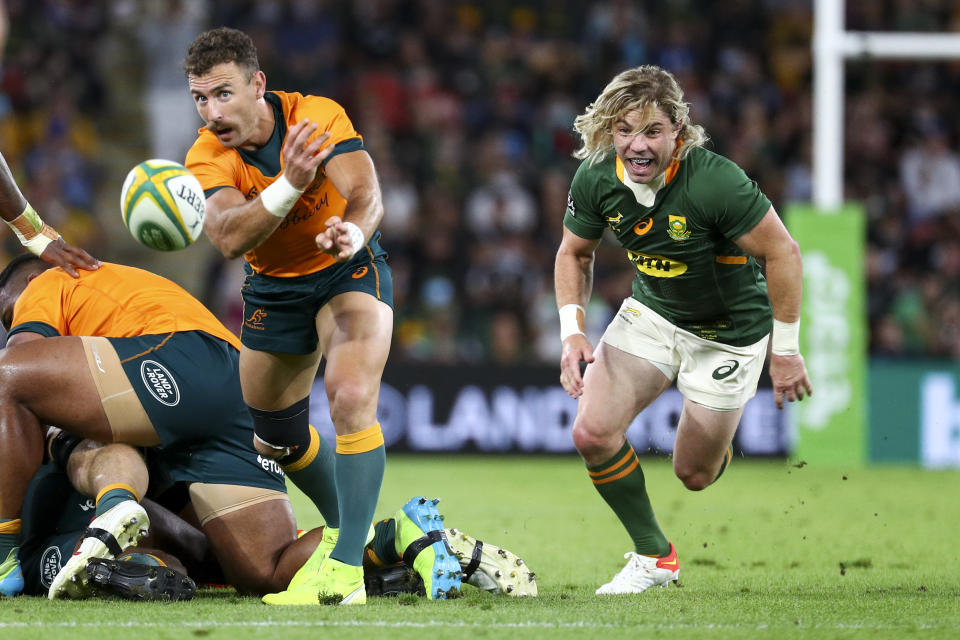 Australia's Nic White passes the ball as South Africa's Faf de Klerk chases during the Rugby Championship test match between the Springboks and the Wallabies in Brisbane, Australia, Saturday, Sept. 18, 2021. (AP Photo/Tertius Pickard)