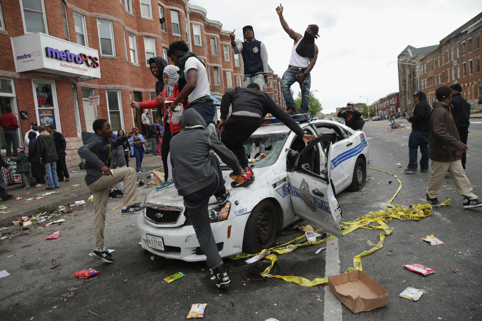 BALTIMORE, MD - APRIL 27:  Demonstrators climb on a destroyed Baltimore Police car in the street near the corner of Pennsylvania and North avenues during violent protests following the funeral of Freddie Gray April 27, 2015 in Baltimore, Maryland. Gray, 25, who was arrested for possessing a switch blade knife April 12 outside the Gilmor Homes housing project on Baltimore's west side. According to his attorney, Gray died a week later in the hospital from a severe spinal cord injury he received while in police custody.  (Photo by Chip Somodevilla/Getty Images)