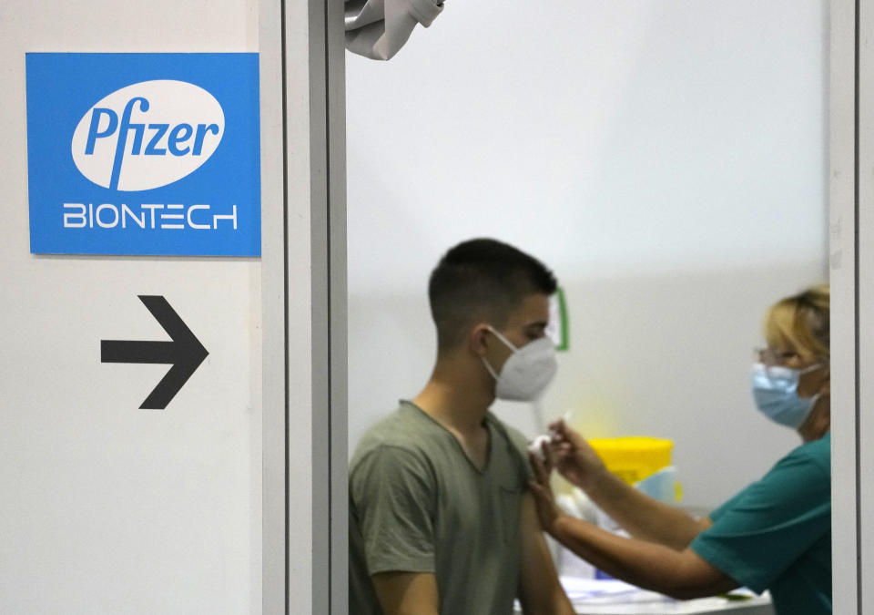 A medical worker administers a shot of Pfizer COVID-19 vaccine to a man at Belgrade Fair makeshift vaccination center in Belgrade, Serbia, Tuesday, Aug. 17, 2021. Serbia has started administering a third, or booster, dose of four different vaccines, including Sinopharm, Pfizer, Sputnik and AstraZeneca, to people who previously were vaccinated at least 6 months ago. (AP Photo/Darko Vojinovic)