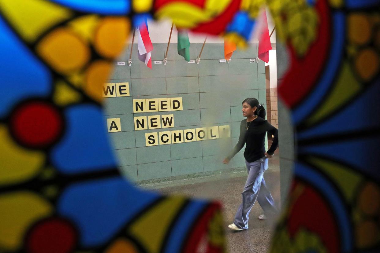 A visitor is framed by partially torn down window decorations as she makes her way past the auditorium during the Rally to Rebuild event Saturday at Akron's North High School.