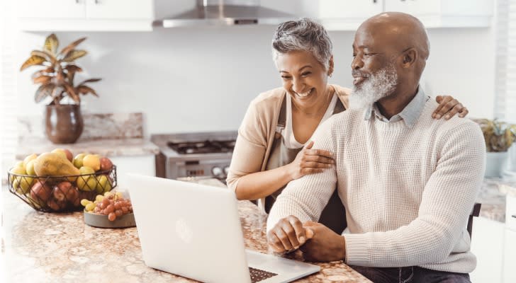 A couple looks over their retirement plan while sitting in their kitchen. 