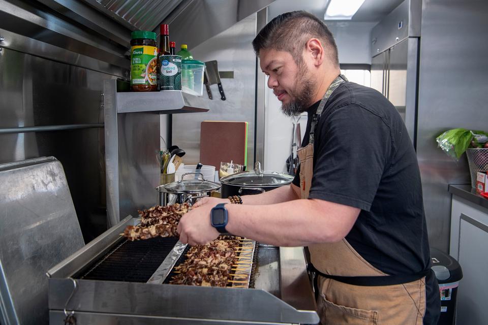 Si Paul Pike, co-owner at chef ng Master BBQ, ay nagdagdag ng mga tuhog ng baboy sa grill sa kanyang food truck sa Zillicoah Brewing Co., Pebrero 8, 2024.