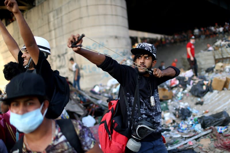 An Iraqi demonstrator uses a sling shot during the ongoing anti-government protests in Baghdad