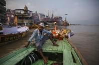 El dueño de un bote donde se realizan cremaciones espera junto a un cadáver que será arrojado el río Ganges en Varanasi, India, el 18 de octubre del 2019. El finado había pedido que lo atasen a una piedra y lo dejasen caer en el río. (AP Photo/Altaf Qadri)