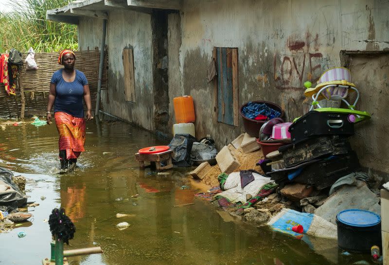 Mrs. Aicha Sy, a resident, walks in the flooded alley of her home after heavy rains in Yeumbeul district on the outskirts of Dakar