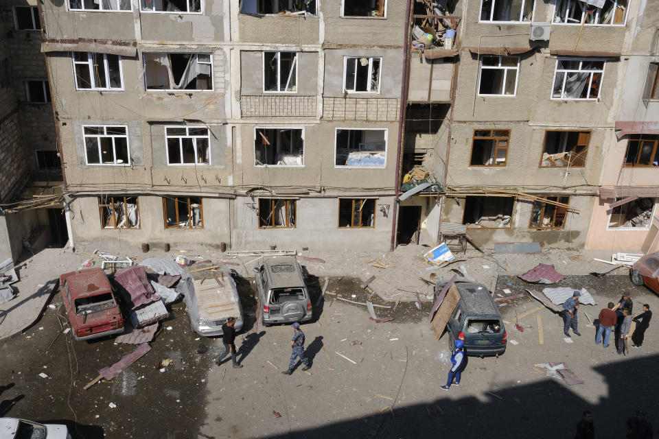 People walk in a residential area that was allegedly damaged by shelling during a military conflict in self-proclaimed Republic of Nagorno-Karabakh, Stepanakert, Azerbaijan, Saturday, Oct. 3, 2020. Armenia and Azerbaijan on Saturday said heavy fighting is continuing in their conflict over the separatist territory of Nagorno-Karabakh. Azerbaijan's president criticized the international mediators who have tried for decades to resolve the dispute. Fighting that started Sept. 27 is the worst to afflict Nagorno-Karabakh and surrounding areas since the 1994 end of a war that left the region in Azerbaijan under the control of ethnic Armenian local forces backed by Armenia. (Aram Kirakosyan/PAN Photo via AP)