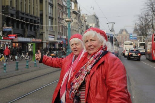 En una callejuela de Ámsterdam, una decena de personas se agolpan para intentar darle la mano a las hermanas gemelas Louise y Martine Fokkens, de 70 años, ambas bisabuelas, consideradas como las prostitutas con mayor edad de Holanda. (AFP/Archivo | Anoek de Groot)