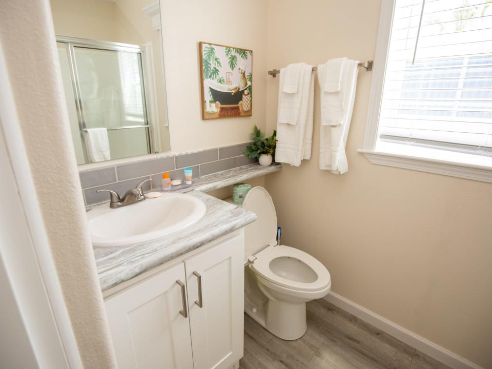 A toilet next to a sink, mirror, towels on the rack.