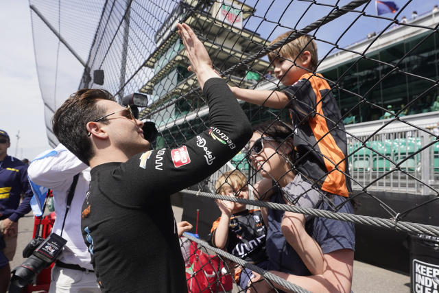 Pato O'Ward, left, of Mexico, gets a high-five from a fan before qualifications for the Indianapolis 500 auto race at Indianapolis Motor Speedway, Sunday, May 22, 2022, in Indianapolis. (AP Photo/Darron Cummings)