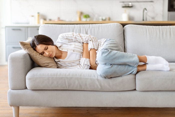 mujer con dolor de tripa en el sofá