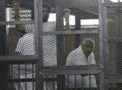 Mohamed Fahmy (R), stands behind bars as he waits to listen the ruling at a court in Cairo June 23, 2014. REUTERS/Asmaa Waguih